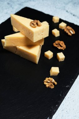Koyu arkaplanda ceviz olan peynir parçaları..