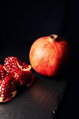 Koyu arkaplanda nar. Yukarıdan bak. Koyu arkaplanda nar suyu. Nar parçacıkları..