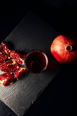 Koyu arkaplanda nar. Yukarıdan bak. Koyu arkaplanda nar suyu. Nar parçacıkları..