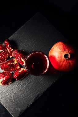 Koyu arkaplanda nar. Yukarıdan bak. Koyu arkaplanda nar suyu. Nar parçacıkları..