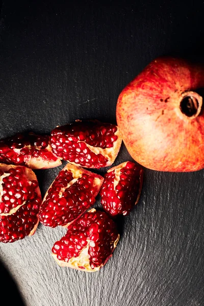 Pomegranate on a dark background. View from above. Pomegranate juice on a dark background. Pieces of pomegranate.