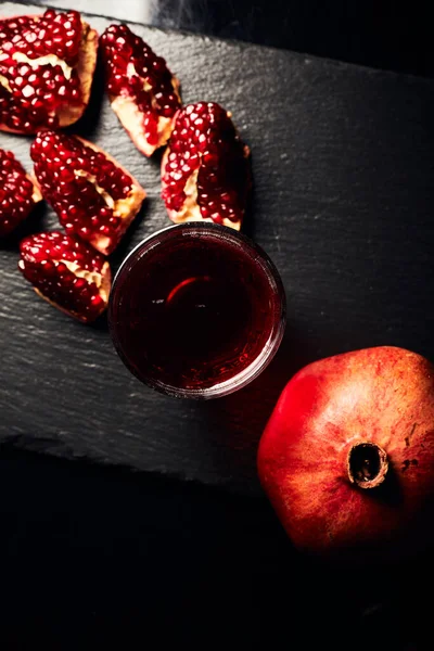 Pomegranate on a dark background. View from above. Pomegranate juice on a dark background. Pieces of pomegranate.