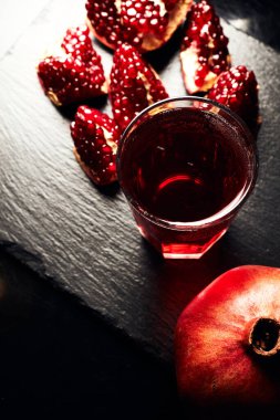 Koyu arkaplanda nar. Yukarıdan bak. Koyu arkaplanda nar suyu. Nar parçacıkları..