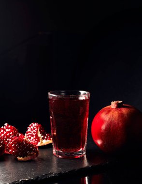 Koyu arkaplanda nar suyu. Koyu arkaplanda nar parçaları. Yaz içeceği.