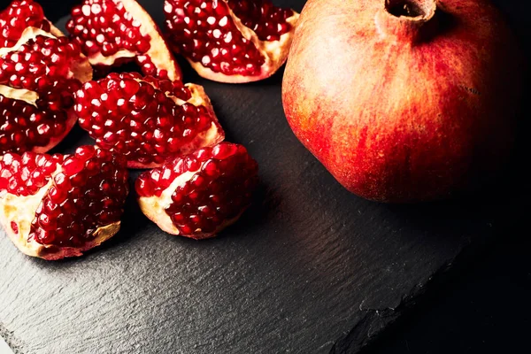 Pomegranate on a dark background. Pieces of pomegranate.