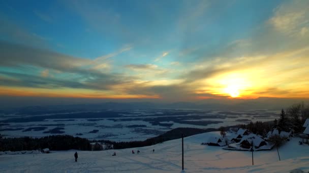 孩子们在雪中玩耍 在一天的末尾 高山上 滑雪中心 当美丽的落日在他们的上方 在天空中 — 图库视频影像