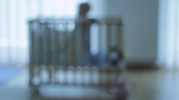 赤ちゃんが遊んでいる赤ちゃんの木製のベッドの焦点のうち 寂しい一人で — ストック動画