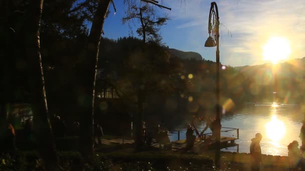 未知の人々のシルエット 一日の終わりに湖を歩く — ストック動画