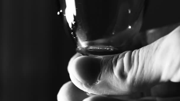 ワイングラスのマクロ 未知の男性の指で開催 可能なアルコール 劇的な光と設定 — ストック動画