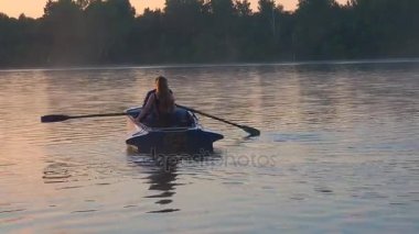 Sevgi dolu birkaç altın günbatımı zamanında Nehri üzerinde bir kürek tekne sürme. Gölün su yüzeyinde güneşin Altın ışık. Gölde altın günbatımı gündoğumu.