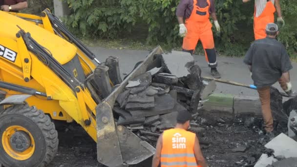 DOMODEDOVO, RUSSIE - 17 MAI 2017 : Les travailleurs de la route chargent des morceaux de vieux bitume dans un seau de bulldozer.. Section de réparation de la surface de la route. Travailleurs enlevés couche d'asphale — Video