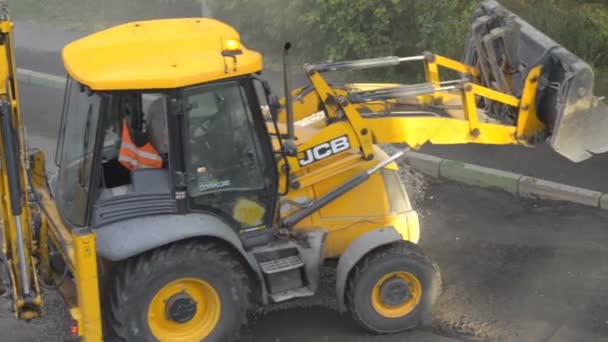 DOMODEDOVO, RÚSSIA - MAIO 17, 2017: Trabalhadores rodoviários carregam pedaços de asfalto antigo em um balde bulldozer.. Seção de reparo da superfície da estrada. Trabalhadores camada removida de asfalto . — Vídeo de Stock