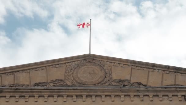 Gruzínská vlajka vlaje ve větru v horní části vládní budovy proti obloze — Stock video