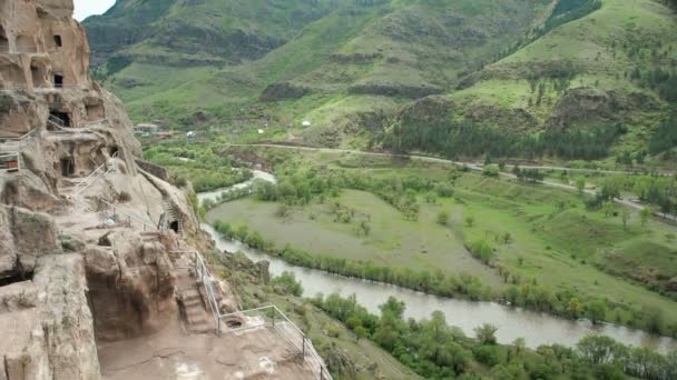 Monasterio de la cueva Vardzia. Complejo tallado en roca. Cueva de la ciudad en las montañas. Vista desde la montaña hasta el río Kura Mtkvari — Vídeo de stock