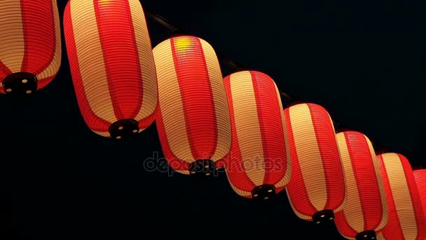 Бумажные красно-белые японские фонари Чочин сияет на темном небе — стоковое видео