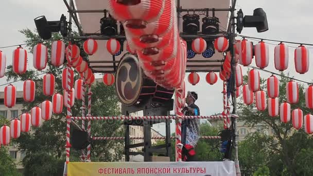 Moskou, Rusland - 16 juli 2017: Spelen muzikanten Aska-Gumi de taiko drums op scène yagura tijdens de Japanse festival. Papieren lantaarns van de rood-witte Chochin landschap voor de vakantie Obon. — Stockvideo