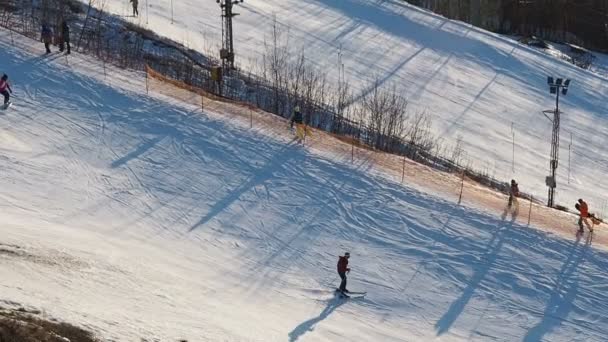 Szkolenia na stoku narciarskiego w mieście. Aktywnych sportów zimowych. Ludzie idą w dół wzgórza na narty i deski snowboardowe. Aktywnych osób zaangażowanych w sporty zimowe w mieście — Wideo stockowe