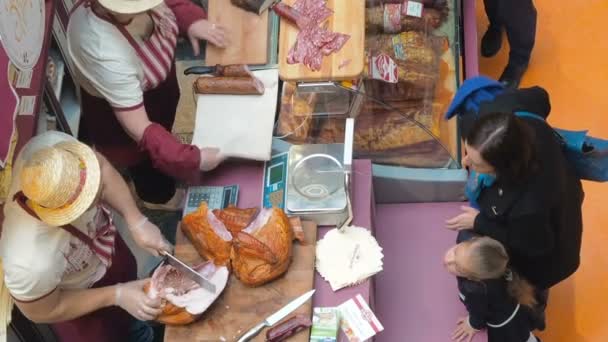 MOSCÚ, RUSIA - 20 DE SEPTIEMBRE DE 2017: Carnicero vendedor vende carne de granjero ahumada salchicha de pavo y jamón para mujer en feria de carne. Carnicería Europa — Vídeos de Stock