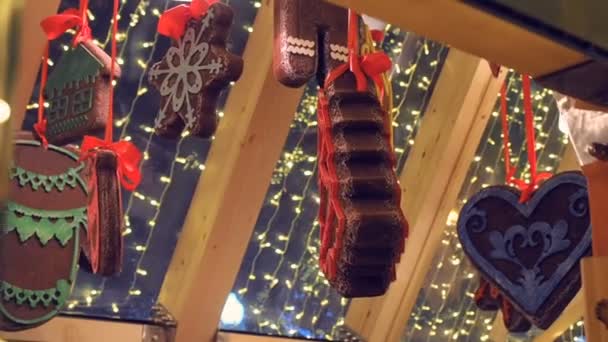 Soubory cookie suvenýry zdobené zimní ornament, hunging maloobchod na vánoční jarmark na ulici. Nový rok pouliční dekorace gingerbread a zářící girlandy — Stock video