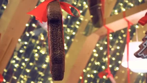 Galletas de recuerdo decoradas con adornos de invierno, el comercio minorista hunging en la feria de Navidad en la calle. Año Nuevo Decoraciones callejeras pan de jengibre y guirnaldas brillantes — Vídeo de stock