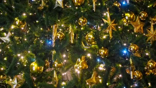 Cierre las luces de un árbol de Navidad brillando por la noche con un fondo fuera de foco. Árbol de Año Nuevo con decoraciones e iluminación. Árbol de Navidad decoraciones fondo — Vídeo de stock