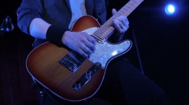 Gece kulübü elektro gitar rock tarzı bir single oynamak adam. yakın çekim. Sahne Alanı'nda müzisyen oyun ahşap elektro gitar