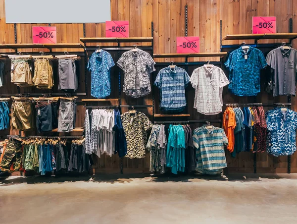 Satır renkli Erkek Konfeksiyon butik alışveriş merkezinde, omuz askıları üzerinde. Giysi rafta asılı. Casual erkek moda ahşap askı üzerinde ayarlayın. Dolap vitrin yüzde 50 indirim