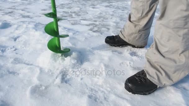 Рибалка свердлить отвір в льоду крупним планом, спортивне рибальство взимку . — стокове відео