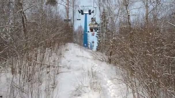 Skidåkare och snouborders på en skidlift pov i vinter skog. Linbanan lyfter folk upp till backen — Stockvideo