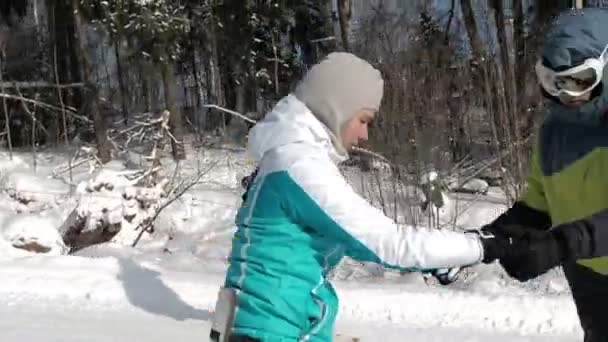 Chica aprendiendo a montar una pendiente cuesta abajo en una tabla de snowboard. Chica joven aprende a hacer snowboard. Cámara en movimiento. Gente en snowbord — Vídeo de stock