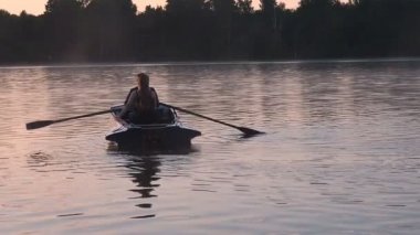 Romantik altın günbatımı nehir Gölü sis sevgi dolu çift küçük kürek teknesi tarihi güzel aşık sırasında mutlu kadın erkek birlikte su doğa çevresinde rahatlatıcı binmek. 25 fps