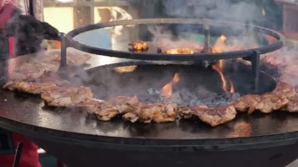 De man-kok verandert vlees op de grill. Mannen koken gegrild vlees. Close-up van de handen van de chef-koks die flip-over rauwe kippenvlees op de ronde barbecue. Straatvoedsel. — Stockvideo
