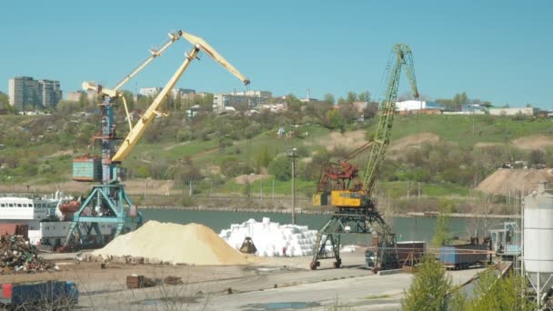 Paesaggio di rimorchiatori e gru nei cantieri navali nel porto di carico. La gru muove la sabbia portata dai camion in un terminal merci. Un grande secchio sta raccogliendo sabbia . — Video Stock