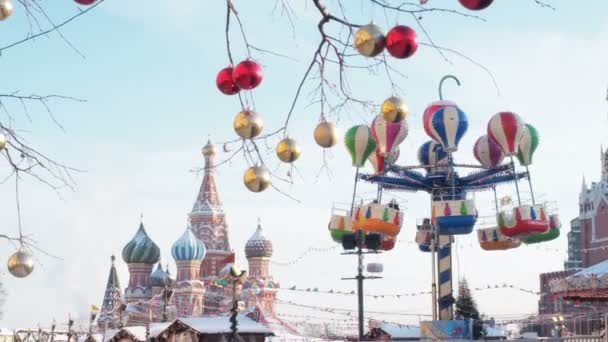 Karussell auf dem Weihnachtsmarkt am Moskauer Kreml auf dem Roten Platz. Weihnachtsmärchen beleuchtete Wende. Der leuchtende Kreisverkehr dreht sich. St. Basilikum-Kathedrale oder Kathedrale von vasily die — Stockvideo