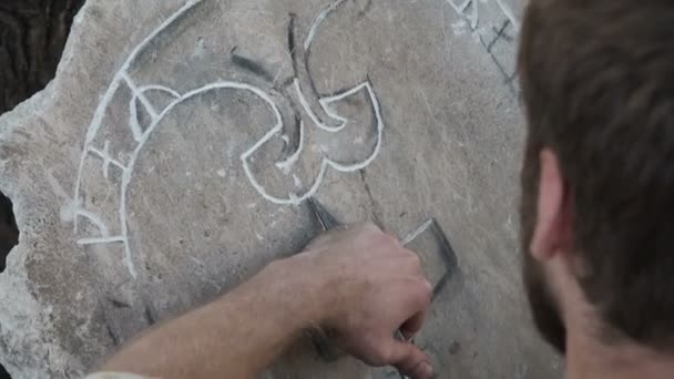Processus de gravure sur pierre. Sculpteur de pierre ou tailleur de pierre crée un motif sur la pierre. Un artisan découpe un ornement sur une dalle de roche à l'aide d'un graveur à main. Le sculpteur sculpte un motif sur une dalle de pierre avec une — Video