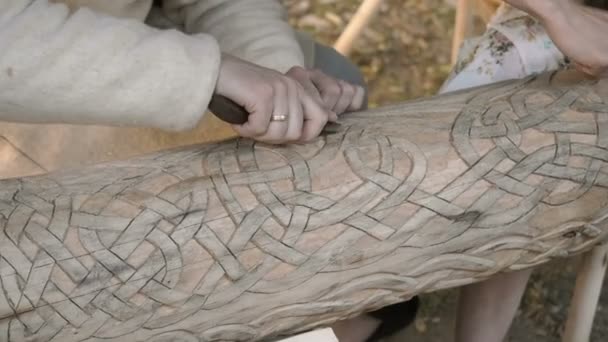 Un tallador de madera talla patrones complicados adornados en un tronco de madera. Cerca de talla de madera increíble — Vídeos de Stock