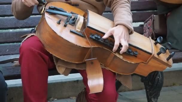 Street musician dressed in vintage ethnic oriental clothes play music on traditional Middle Eastern musical instrument hurdy-gurdy also named wheel fiddle, wheel vielle — Stock Video