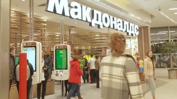 Moskva, Ryssland - 11 november 2019: Människor går till en snabbmatsrestaurang Mcdonalds i Mega köpcentrum i Moskva. Vissa människor gör en snabb beställning genom självbetjäning kiosk nära — Stockvideo