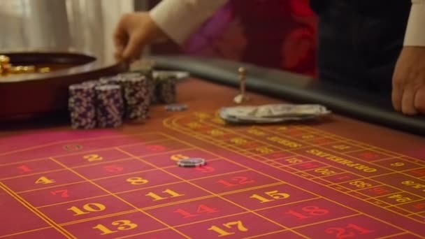 Los jugadores recogen sus ganancias y hacen nuevas apuestas en el casino. El jugador intercambia dinero con el crupier por jugar fichas. Diseño de mesa de ruleta con poca luz — Vídeos de Stock