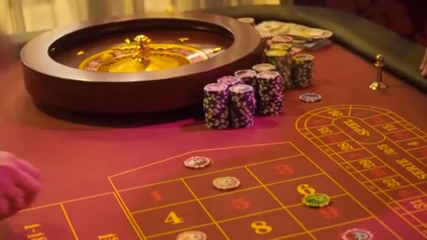 Игроки выбирают ячейки с числами и делают новые ставки на красный цвет в казино. Размещение стола в рулетке при низком освещении — стоковое видео