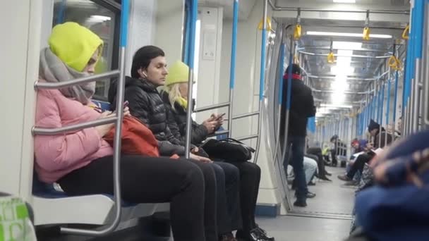 MOSCOW, RUSSIA - NOVEMBER 21, 2019: Gerakan carriag kereta metro. Orang-orang dengan pakaian hangat duduk di gerbong bawah tanah menggunakan smartphone. Seorang pria duduk berpikir tentang sesuatu, Gadis dan wanita — Stok Video