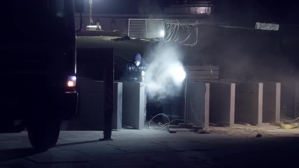 Il lavoratore urbano in uniforme e bendaggio protettivo taglia smerigliatrice lastra di cemento durante la notte. Costruzione di strade in una grande città — Video Stock