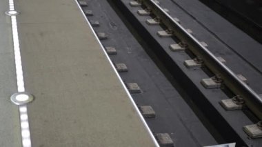 Yeraltı treni alçak açıyla yaklaşır. Tren metro istasyonuna varır. Platformda yanıp sönen ışıklar yaklaşan treni işaret ediyor.