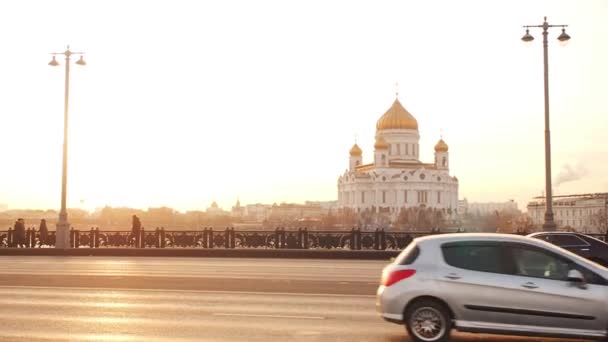 Moskau, Russland - 23. November 2019: Blick von der großen Steinbrücke auf die Kathedrale von Christus dem Erlöser in Moskau im goldenen Sonnenuntergang. Verkehr in einer Großstadt. die Bewegung der Autos auf einer Breitbandverbindung — Stockvideo