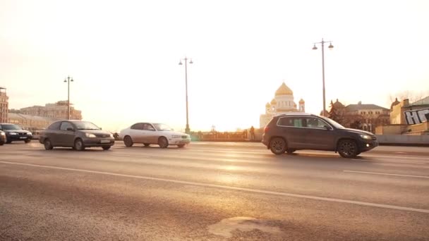 Moskva, Ryssland - 23 november 2019: Utsikt från Big Stone Bridge till Kristi Frälsares Domkyrka i Moskva i solnedgången gyllene tid. Trafiken i en storstad. Förflyttning av bilar på bredband — Stockvideo