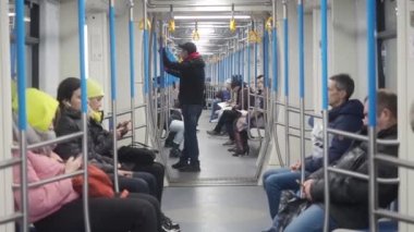 Moskova, Rusya - 21 Kasım 2019: Metro tren taşımacılığı. Sıcak giysili insanlar yeraltı vagonlarında oturuyorlar ve akıllı telefonlar kullanıyorlar. Bir erkek oturup bir şey düşünür, kız ve kadın.