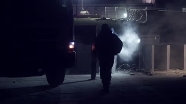 Il lavoratore urbano in uniforme e bendaggio protettivo taglia smerigliatrice lastra di cemento durante la notte. Un altro uomo sale su un camion. Costruzione di strade in una grande città — Video Stock