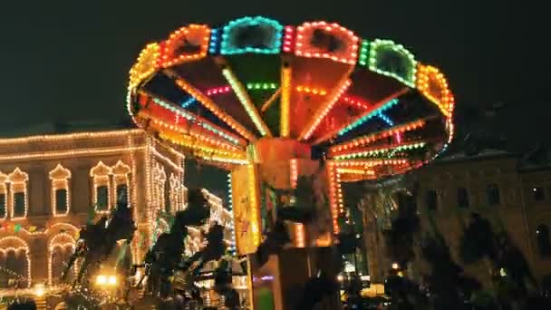 Die Menschen haben Spaß und feiern Neujahr auf dem Roten Platz, Reiten auf einem Karussell schönen bunten leuchtenden Karussell dekoriert und für die Winterferien arrangiert. Weihnachtsfee illuminiert — Stockvideo