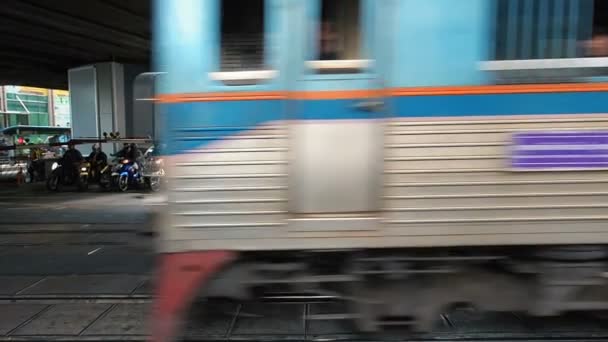 Viele vorbeifahrende Eisenbahnwaggons auf Gleisen mit teilweise stadtbildprägenden Gebäuden im Hintergrund. ein Zug, der vor einem Bahnübergang vorbeifährt. fegt vorbei. Waggons fegen auf einem Bahnübergang in — Stockvideo