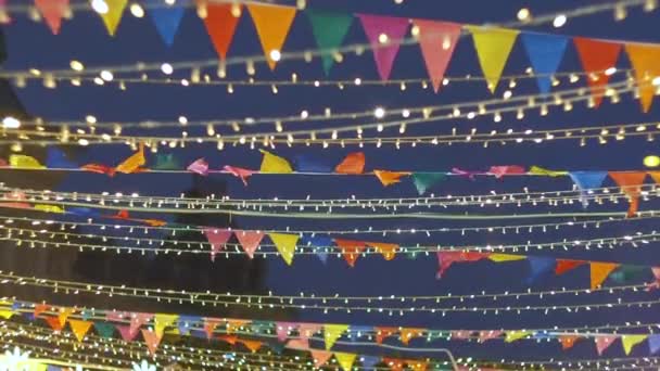 Many small colorful flags swaying in the wind and electric light garlands decorating the city. Holiday decorations on Red Square. Festive abstract background — Stock Video